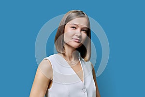 Portrait of young elegant business woman, on blue studio background