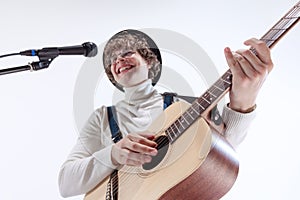 Portrait of young emotiona man, musician playing acoustic guitar and singing. Concept of art, music, style and creation photo