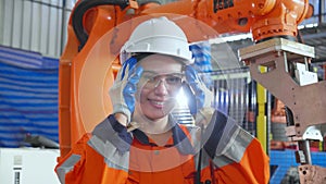 Portrait young engineer asian woman wearing glasses and smile with success of robot arm in factory industry, inspector or worker