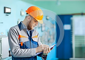 Portrait of young engineer taking notes at control room