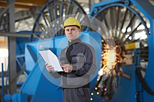 Portrait of young engineer taking notes in factory warehouse roo