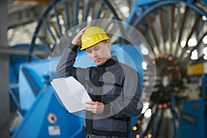 Portrait of young engineer taking notes in factory warehouse roo