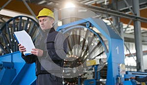 Portrait of young engineer taking notes in factory warehouse roo