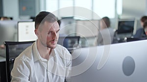 Portrait of Young Entrepreneur in Open Space Office Working on Decktop Computer. Male Professional Typing on PC Keyboard