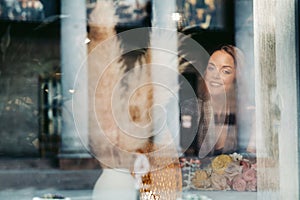 Portrait of a young European girl with long hair in a cafe sitting near the window, a tall girl in a jacket with long hair in the