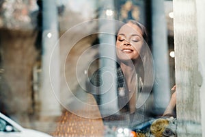 Portrait of a young European girl with long hair in a cafe sitting near the window, a tall girl in a jacket with long hair in the