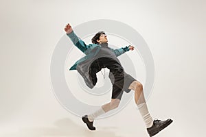 Portrait of young expressive man in stylish outfit posing  over grey studio background