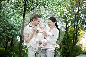 Portrait of a young family with a child. Happy young family spending time outdoor on a summer day. Happiness and harmony
