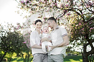 Portrait of a young family with a child. Happy young family spending time outdoor on a summer day. Happiness and harmony