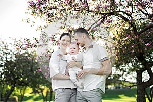 Portrait of a young family with a child. Happy young family spending time outdoor on a summer day. Happiness and harmony