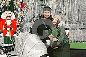 Portrait of a young family, a man and a woman with a stroller on a walk on a winter day