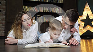 Portrait of young family mom, son and dad are reading a book together.
