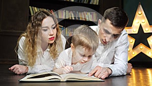 Portrait of young family mom, son and dad are reading a book together.