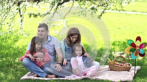 Portrait of a young family. parents spend time with their children outdoors. a picnic under a blossoming Apple tree.