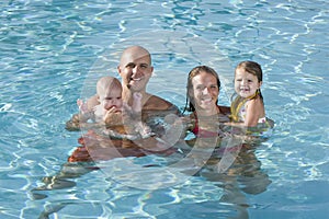 Portrait of young family smiling in swimming pool