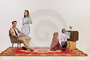 Portrait of young family watching TV isolated over grey background. Kids watching cartoons.