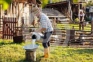 Portrait of young farmer pours milk into can at his elocogical farm. Concept of milk production and agriculture business