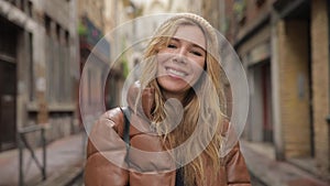 Portrait of a young fashionable beautiful young millennial woman shows the Peace sign and tongue smiles at the camera on