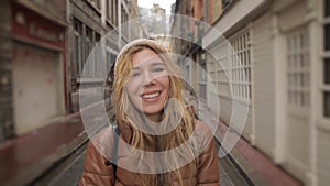 Portrait of a young fashionable beautiful young millennial woman shows the tongue smiles at the camera on the street of