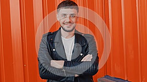 Portrait of young fashionable positive man standing near orange wall background