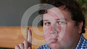 Portrait of a young fat man having idea and pointing finger up in cafe or restaurant