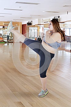 Fat woman performing a kick in gym center