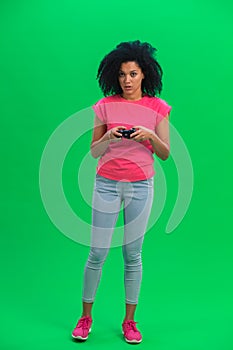 Portrait of young female African American playing a video game using a wireless controller. Black woman with curly hair