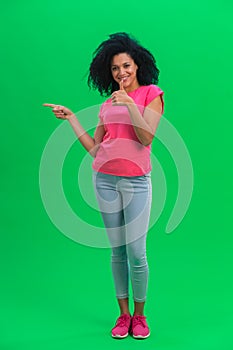 Portrait of young female African American pointing side hand for something and shows thumb like. Black woman with curly