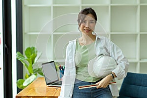 Portrait of young female architect with hardhat and ruler in modern engineers office
