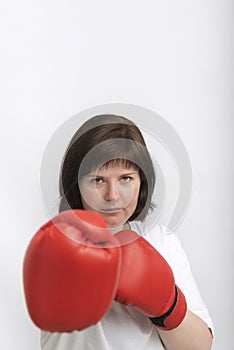 Portrait of young female boxer in red gloves on white background. Struggle for womens rights, feminism