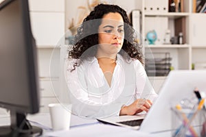 Portrait of young female business employee writing and working with laptop