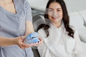 Portrait of young female dentist standing by mid adult woman in clinic. Female dentist repairing patient tooth in dental ambulant