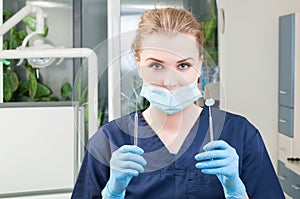 Portrait of young female dentist with tools in dental clinic