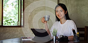 Portrait of young female designer is sitting at graphic studio in front of laptop computer while working online