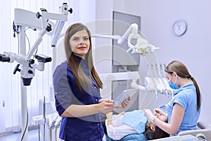 Portrait of young female doctor dentist with digital tablet in dental office