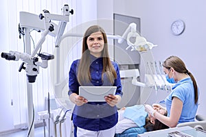 Portrait of young female doctor dentist with digital tablet in dental office