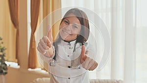 Portrait of a young female doctor in a good mood who shows thumbs up.