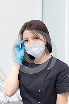 Portrait of a young female doctor in a medical mask is taken off and put on. Medical face mask professional breathing
