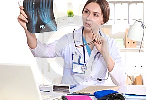 Portrait of young female doctor sitting at desk in hospital