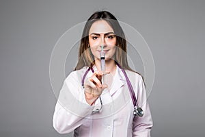 A portrait of a young female doctor smiling with a syringe in her hand. Portrait of a beautiful woman doctor on grey