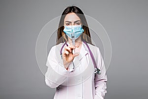A portrait of a young female doctor smiling with a syringe in her hand. Portrait of a beautiful woman doctor on grey