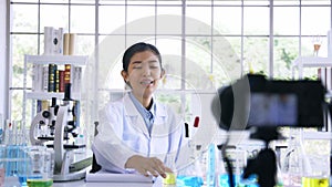 Portrait of young female doctor wearing labcoat recording online video class and vlog on medical research and science