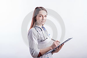 Portrait of a young female doctor in a white uniform with a folder and a pen in hands in the studio on a white background.