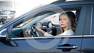 Portrait of young female driver looking out the open window while driving a car