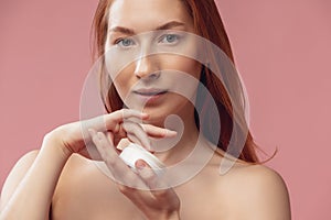 Portrait of young female fashion model isolated on prink studio background. Beautiful caucasian redheaded woman with