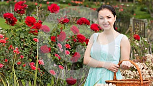 Portrait of young female holding a basket near roses in outdoors