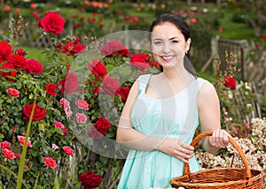 portrait of young female holding a basket near roses in outdoors