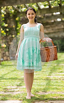 portrait of young female holding a basket near roses in outdoors