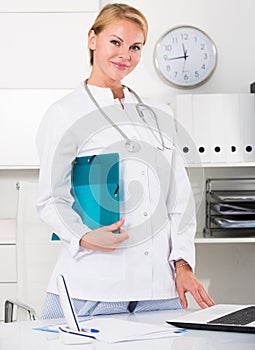 portrait of young female medic with clipboard in doctor's office