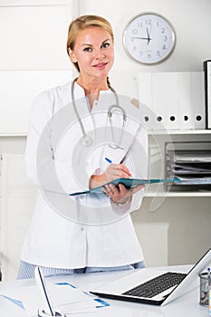portrait of young female medic with clipboard in doctor's office
